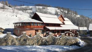 a building covered in snow with a stone fence at Cabana Daianna si Jessica in Poiana Vadului