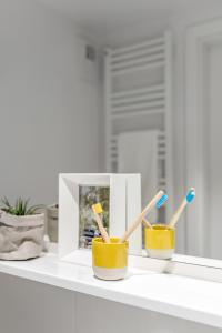 two toothbrushes sitting on top of a white cup at Apartamenty Depot Gdańsk in Gdańsk