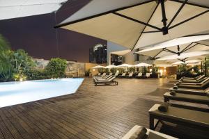 ein Hotel mit einem Pool, Sonnenschirmen und Stühlen in der Unterkunft Hotel Trópico in Luanda