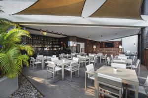 a restaurant with white tables and chairs and a bar at Hotel Trópico in Luanda