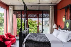 Amdaeng Bangkok Riverside Hotel - SHA Plus Certified في بانكوك: غرفة نوم بجدران حمراء وسرير ونافذة