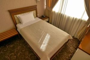 a small bedroom with a bed with a window at Rozafa Hotel in Shkodër