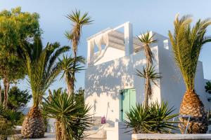 a white house with palm trees in front of it at Kostantakis Residence & Winery in Pollonia
