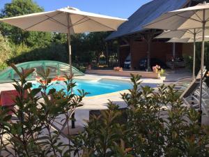 a swimming pool with two umbrellas next to a house at TESS Villa Fournadin in Fournaudin