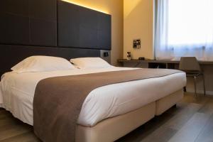 um quarto com uma cama grande e uma grande cabeceira. em City Hotel & Suites em Foligno