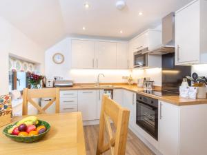 a kitchen with white cabinets and a bowl of fruit on a table at Bay Tree Cottage in Droitwich