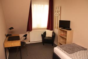 a bedroom with a bed and a desk and a television at Landhaus Riedel in Papenburg