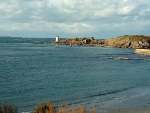 a body of water with a lighthouse in the distance at Hotel Au Bout Du Monde in Le Conquet