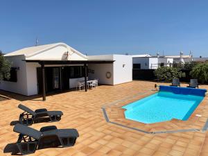 a swimming pool with chairs and a house at Casas Tomare I in San Bartolomé