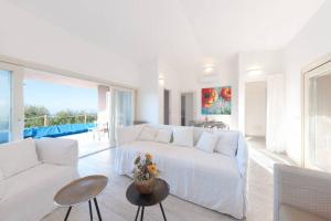 Sala de estar blanca con sofá blanco y mesa en VILLA ASFODELO-INFINITYHOLIDAYS, en Costa Paradiso