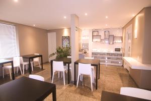 a kitchen and dining room with tables and white chairs at Hotel Alpha in Uberlândia