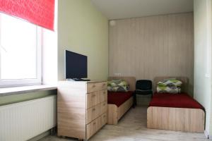 a small room with two beds and a television at Hostelis Laurita in Kaunas