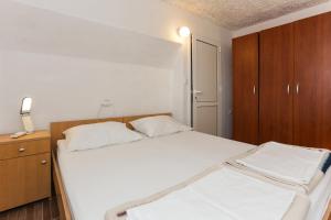 a bedroom with a white bed and a wooden cabinet at Lapad View Apartments in Dubrovnik