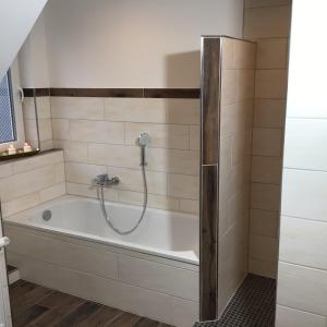 a bathroom with a bath tub with a shower at HaRe Ferienwohnungen in Langeneß +60 photos