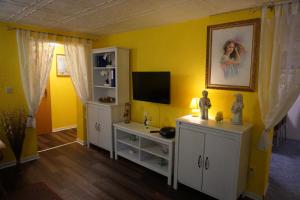 uma sala de estar com paredes amarelas e armários brancos e uma televisão em Haus Stricker em Sagard