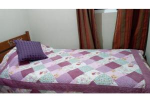 a bed with a purple quilt and a purple pillow at Casa el Tihue Puerto Varas in Puerto Varas