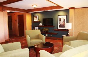 ein Wohnzimmer mit Stühlen, einem TV und einem Sofa in der Unterkunft Auburn Place Hotel & Suites Cape Girardeau in Cape Girardeau