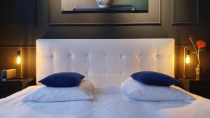 a white bed with two blue pillows on it at Residenz Stadslogement in The Hague