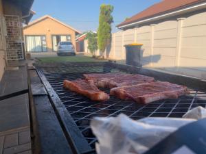 three pieces of meat cooking on a grill at Happy Living Guesthouse in Vereeniging