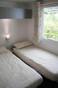 two beds in a room with a window at Mobile Homes by KelAir at Camping Sylvamar in Labenne +31 photos