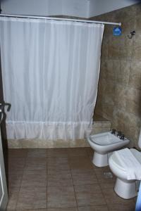 y baño con aseo y cortina de ducha. en Hostería Anchimalen en Villa Gesell