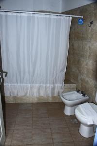 a bathroom with a toilet and a shower curtain at Hostería Anchimalen in Villa Gesell +68 photos