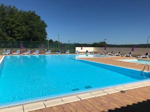 een groot zwembad met stoelen en blauw water bij Camping Paradis de Maillac in Sainte-Nathalène