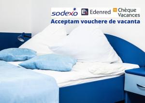 Cama con sábanas y almohadas azules y blancas en Club Onix Apartments, en Neptun