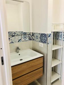 un bagno con lavandino bianco e piastrelle bianche e blu di Casa Le Soleil a Ischia