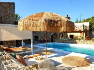 a resort with a swimming pool with a straw umbrella at Las Fincas de Annie in Felanitx