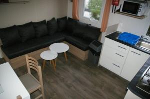 a living room with a black couch and two tables at mobil home 32 m² 4/6p in Onzain