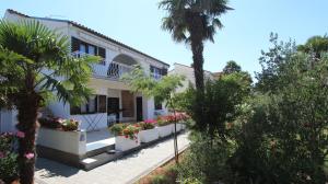 uma casa branca com uma palmeira e flores em Apartments Miro em Vantacići