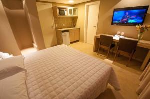a hotel room with a bed and a table and a television at Viageiro Casa Hotel in Pelotas