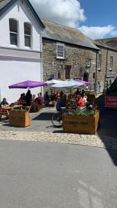 a group of people sitting at tables with purple umbrellas at The Ship Inn Fowey in Fowey
