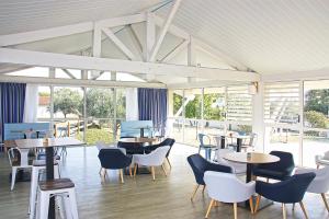 un restaurant avec des tables, des chaises et des fenêtres dans l'établissement Azureva Fouras, à Fouras