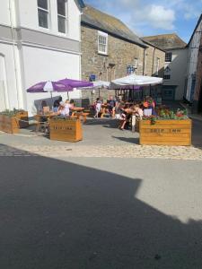 um grupo de pessoas sentadas em mesas com guarda-chuvas em The Ship Inn Fowey em Fowey