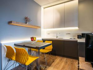 una cucina con sedie gialle e un tavolo con lavandino di TATRA SUITES Luxury Studio A303 a Starý Smokovec