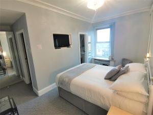 1 dormitorio con 1 cama y TV en la pared en Anglesey House, en Llandudno