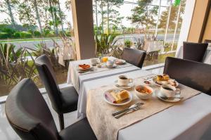 un comedor con 2 mesas con platos de comida en Viageiro Casa Hotel, en Pelotas