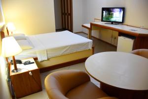 um quarto com uma cama e uma secretária com um computador em Hotel Grão Para em Belém