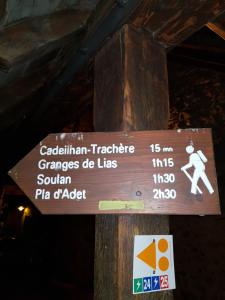a sign on a wooden pole with a pedestrian sign at Joli petit appartement au calme in Vignec