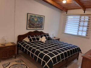 1 dormitorio con 1 cama con edredón blanco y negro en La Posada del Aromito - Suite, en Quito
