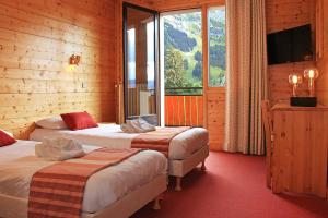 Habitación de hotel con 2 camas y ventana grande. en Azureva La Clusaz les Confins en La Clusaz