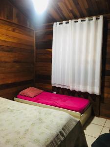 a room with a bed and a window with a curtain at Casa de Madeira com Fogão a Lenha lagoa no fundo para 8 pessoas in Morada Nova de Minas