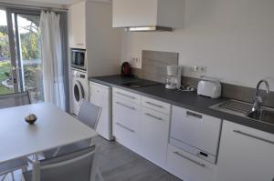 a kitchen with white appliances and a table with chairs at le petit domaine 07 in Les Vans