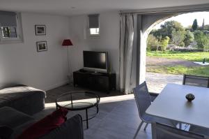 a living room with a couch and a tv at le petit domaine 07 in Les Vans