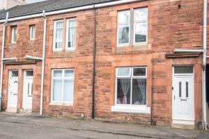 a brick building with white doors and windows at Station Apartment in Bellshill