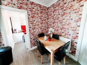 a dining room with a brick wall and a wooden table at Station Apartment in Bellshill