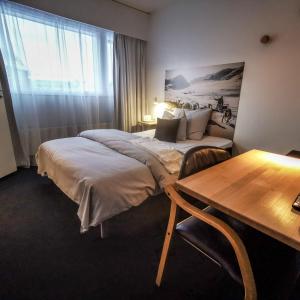 a hotel room with a bed and a desk and a table at Hotel Sisimiut in Sisimiut