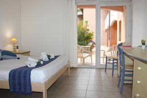 Un dormitorio con una cama y un escritorio y un balcón. en Azureva La Londe les Maures, en La Londe-les-Maures
